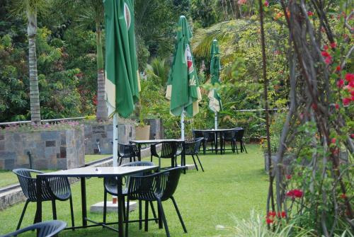 a group of tables and chairs with an umbrella at Kiriri Garden Hotel in Bujumbura