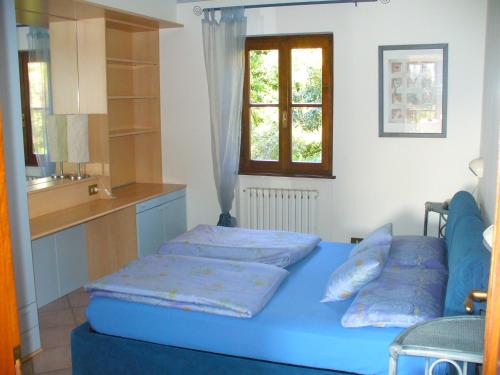 a bedroom with a blue bed and a kitchen at Casa Marica in Porto Valtravaglia