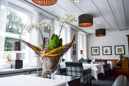 a vase of flowers on a table in a restaurant at Hotel Landhaus Säntis Herisau in Herisau