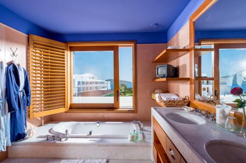 a bathroom with a sink, tub, mirror and window at Elounda Beach Hotel & Villas, a Member of the Leading Hotels of the World in Elounda