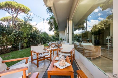 a patio with wooden chairs and tables and windows at Verdeluna ApartHotel in Marina di Pietrasanta