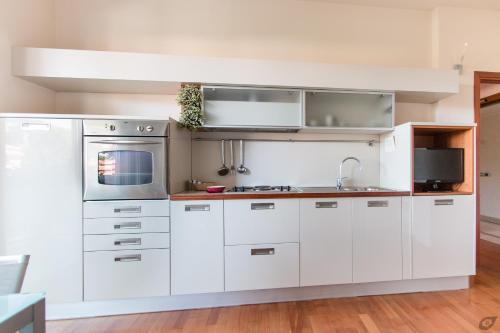 a kitchen with white cabinets and a microwave at Verdeluna ApartHotel in Marina di Pietrasanta
