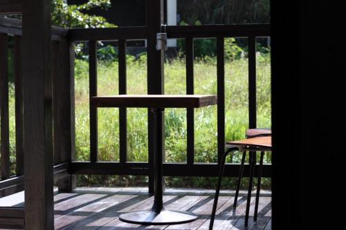 a table and a chair on a screened porch at Nangoku Lodge Booya in Onna