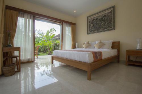 een slaapkamer met een bed en een groot raam bij Yudha Ubud in Ubud