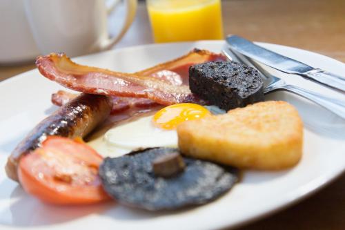 a plate of breakfast food with an egg and bacon at Best Western Plus Centurion Hotel in Midsomer Norton