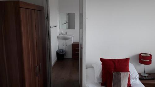 a bedroom with a bed and a bathroom with a sink at Alexandra Guest House in Hemel Hempstead