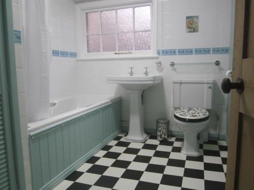 a bathroom with a sink and a tub and a toilet at Milliner's Cottage in York