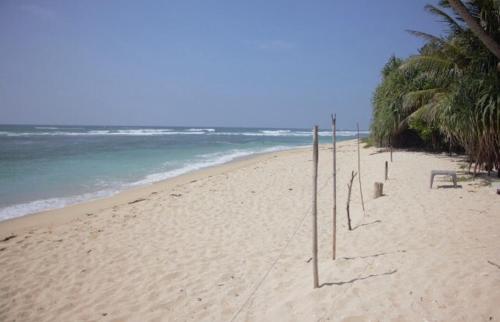 a sandy beach with a line of volleyball nets at Blue Corals Beach Bungalow in Madihe East