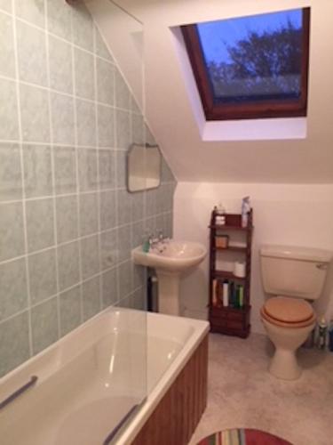 a bathroom with a toilet and a tub and a sink at Southfield House in Hornsea