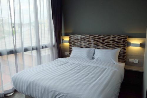 a bedroom with a bed with white sheets and a window at V Varee Bangkok in Bangkok