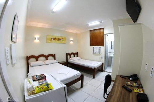 a small room with two beds and a table and a table sidx sidx at Hotel Belem Fortaleza in Fortaleza