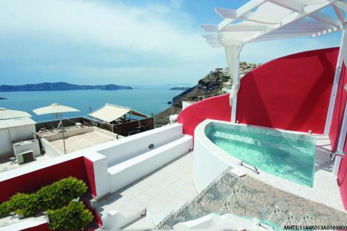 a balcony overlooking a beach filled with lots of blue umbrellas at Theoxenia Caldera Hotel in Fira