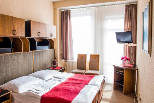 a bedroom with a large bed with a red blanket at Hotel Kamei in Snina