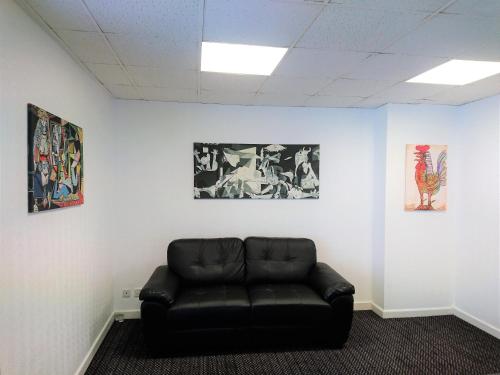 a black leather couch in a room with pictures at Sarum Apart-Hotel in Saint Helier Jersey