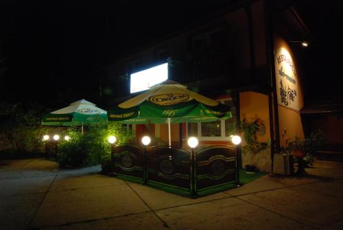 a restaurant with an umbrella on the sidewalk at night at Hotel La-Musica in Piaseczno