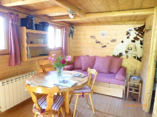 een woonkamer met een paarse bank en een tafel bij Chalet Fleur des Neiges in Saint-Jean-dʼAulps