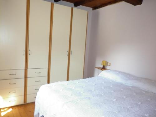 1 dormitorio con 1 cama blanca y armarios blancos en La casa del girasole, en Piazza al Serchio