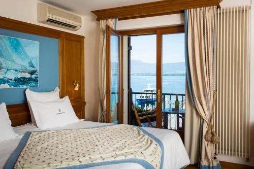 a bedroom with a bed and a view of the ocean at Hôtel Restaurant Du Port in Yvoire