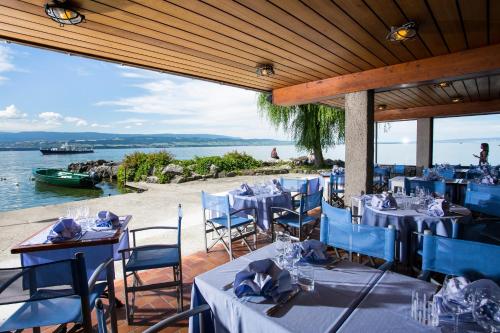a restaurant with blue tables and chairs and the water at Hôtel Restaurant Du Port in Yvoire