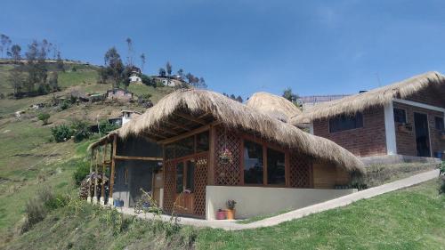 a house with a thatched roof on a hill at Turismo Comunitario La Esperanza in Colta
