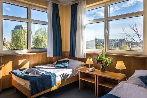 a hotel room with two beds and two windows at Jagelló Business Hotel in Budapest