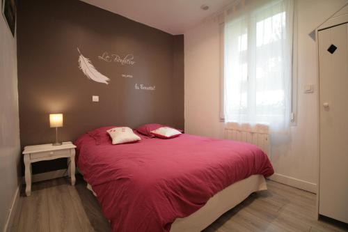 una camera da letto con un letto con una coperta rossa e una finestra di Gîte Côte Fleurie Lisieux Centre a Lisieux