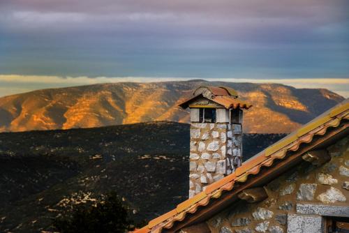 a tower on the roof of a building with mountains in the background at Abelos Villas in Áyios Ioánnis