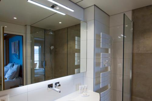 ein Badezimmer mit einem Spiegel und einem Waschbecken in der Unterkunft Hôtel Restaurant Du Port in Yvoire