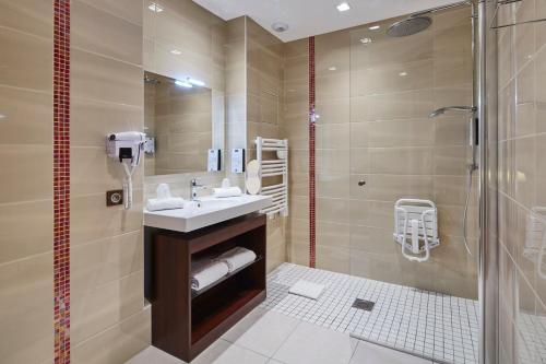 a bathroom with a sink and a shower at Kyriad Nantes Sud - Bouaye Aéroport in Bouaye
