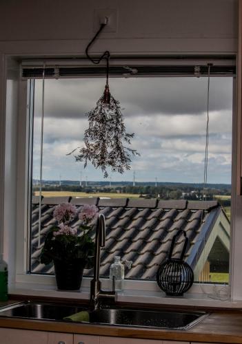 a kitchen window with a sink and a view of a roof at Stall Hällarp in Falkenberg