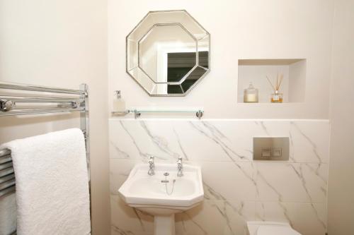 a white bathroom with a sink and a mirror at Victoria House in Stow on the Wold