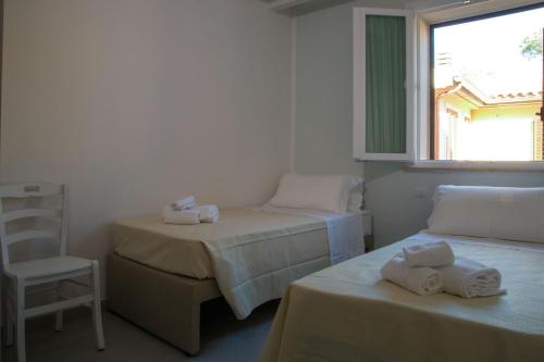 a room with two beds and a chair and a window at La Residenza del Golfo in Puntone di Scarlino