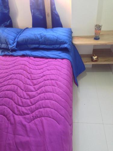 Apartamento Tolu في تولو: سرير مع لحاف أرجواني وأزرق