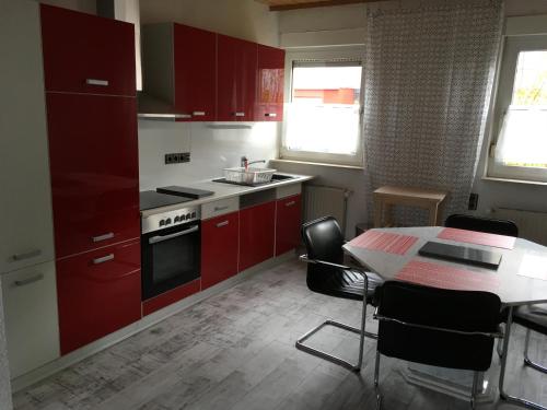 イダー・オーバーシュタインにあるKRIO Nicola Rothfuchs Ferienwohnung 1のキッチン(赤いキャビネット、テーブル、椅子付)