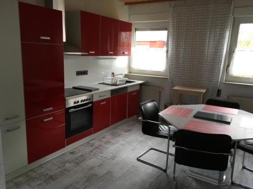 a kitchen with red cabinets and a table with chairs at KRIO Nicola Rothfuchs Ferienwohnung 1 in Idar-Oberstein