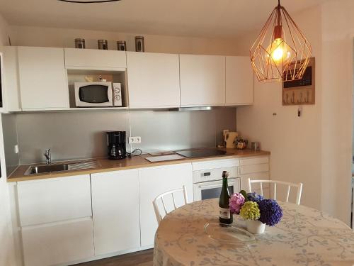 eine Küche mit weißen Schränken und einem Tisch mit Blumen darauf in der Unterkunft Côte de Granit Rose in Perros-Guirec