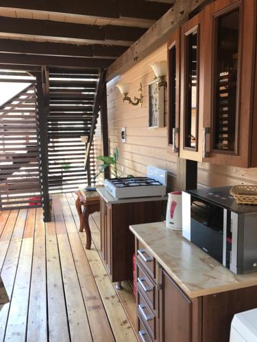 a kitchen with a stove and a wooden floor at Guest House na Vozba 9A in Gudauta