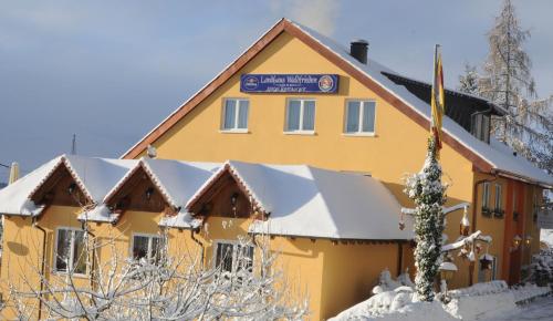 a yellow building with snow on the roof at Landhaus Waldfrieden in Tengen