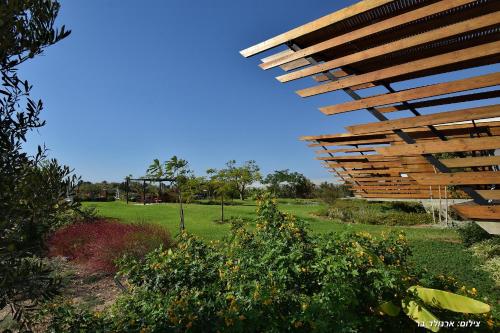 a wooden roof over a garden with a green field at Halom Be'Dor in Dor