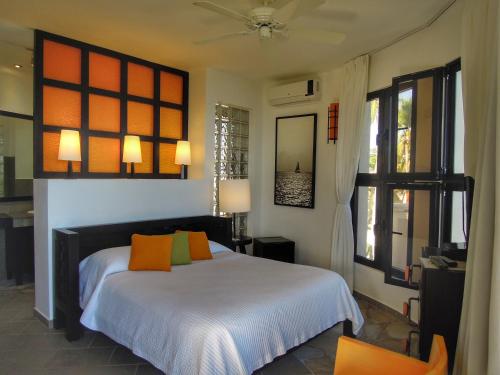 een slaapkamer met een bed met oranje en groene kussens bij El Magnifico in Cabarete
