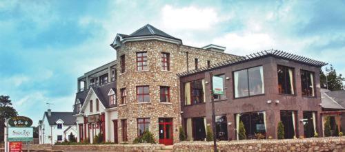 a large brick building with a red door at Upton Court Hotel in Kilmuckridge