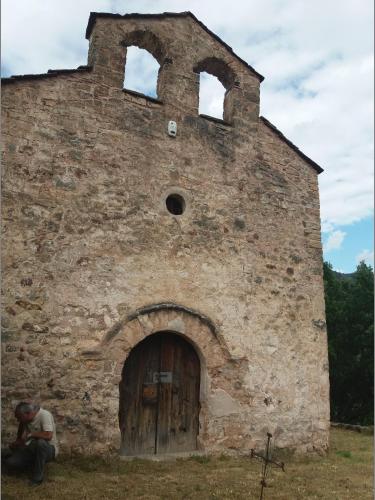 a man sitting in front of a brick building at Casa Rural Molí de Fòrnols in Fornols