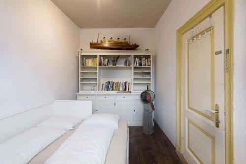 カンペンにあるJuttershoekの白いベッド2台と本棚が備わる客室です。