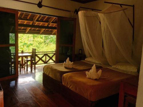 two beds in a room with a table and a window at Ban Vivanh chambres d'hotes in Luang Prabang