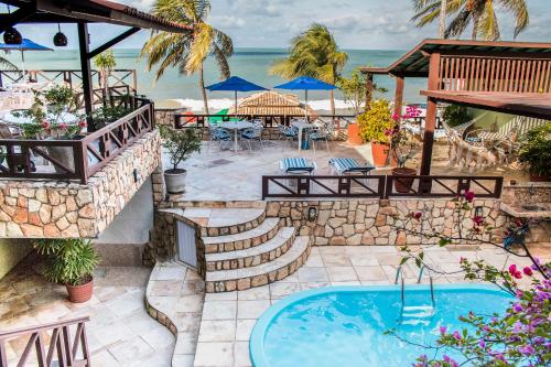 a patio with a swimming pool and the ocean at POUSADA TIA LUCY in Natal