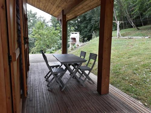 a wooden porch with a picnic table and two chairs at Le Barail 31 in Couret