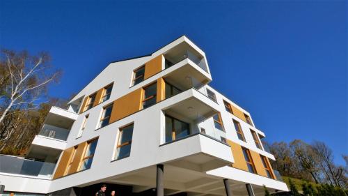a white building with orange windows against a blue sky at Apartamenty Willowa in Szczyrk