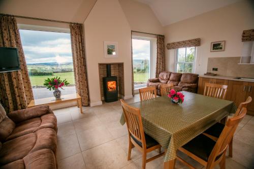 a living room with a table and a fireplace at Strule Cottage in Strabane