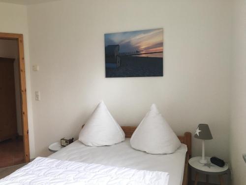 a bedroom with a bed with white pillows on it at Haus Hugo Zingst in Zingst