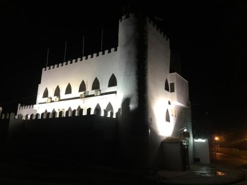 a white building with lights on it at night at El Castillo in Alcalá de Guadaira